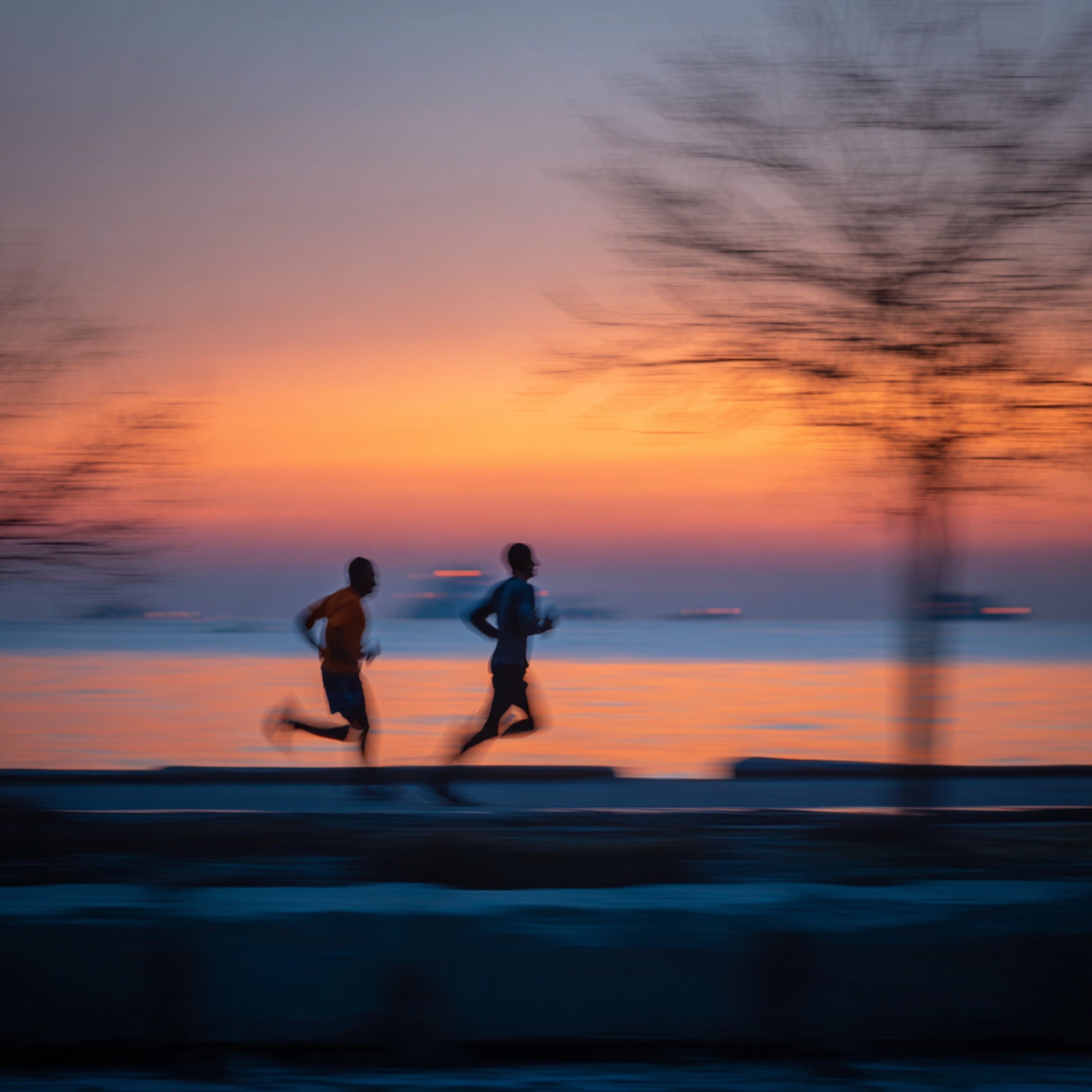 Early morning runner sprinting on lakefront trail at dawn
